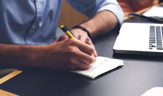 This image shows a man writing meeting notes