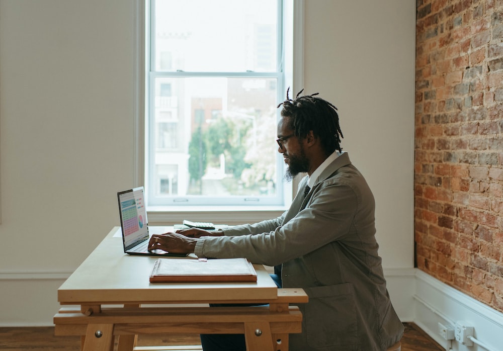 a person sitting at a desk with a laptop and papers doing remote closing jobs, remote closer