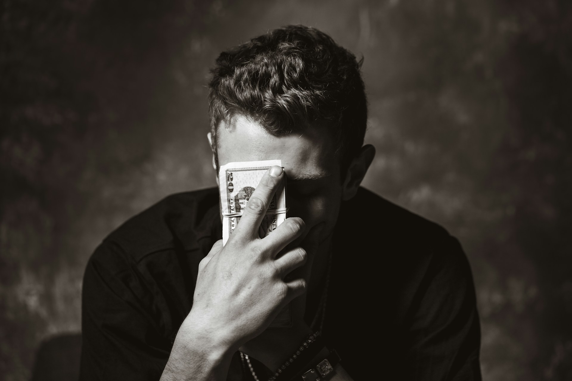 man holding money in front of his face