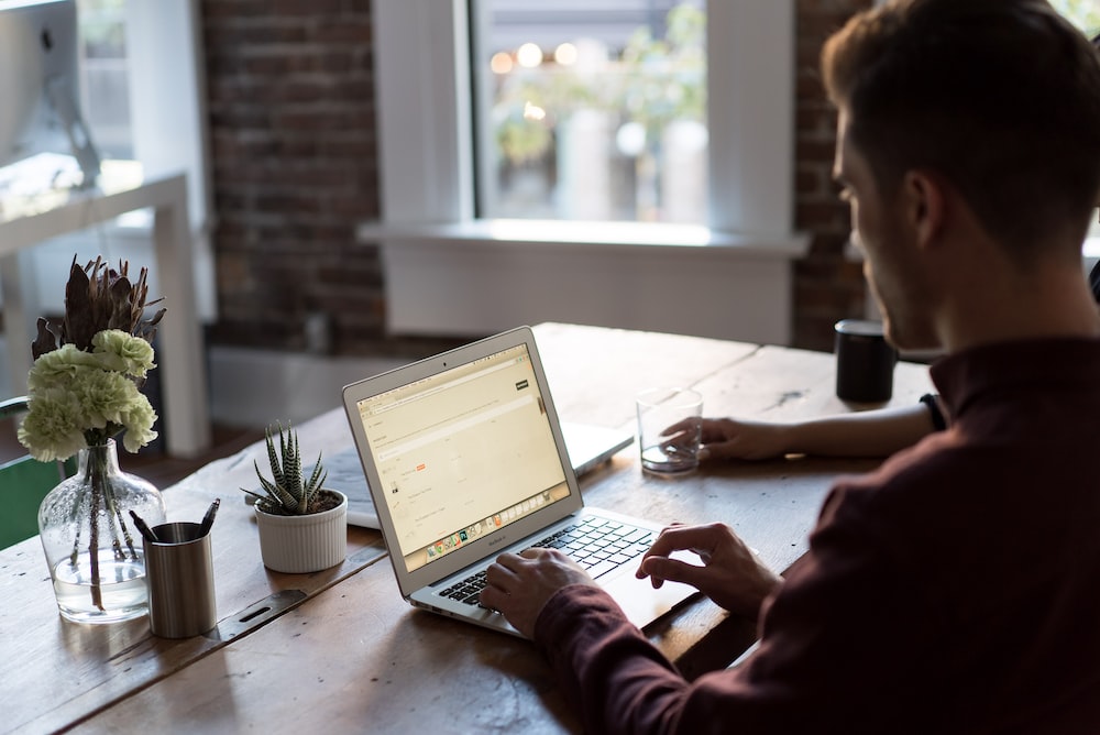man operating laptop on top of table, doing remote closing jobs