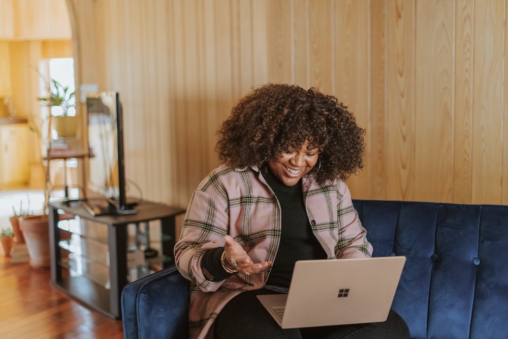 person sitting on couch holding a Surface device doing remote closing jobs