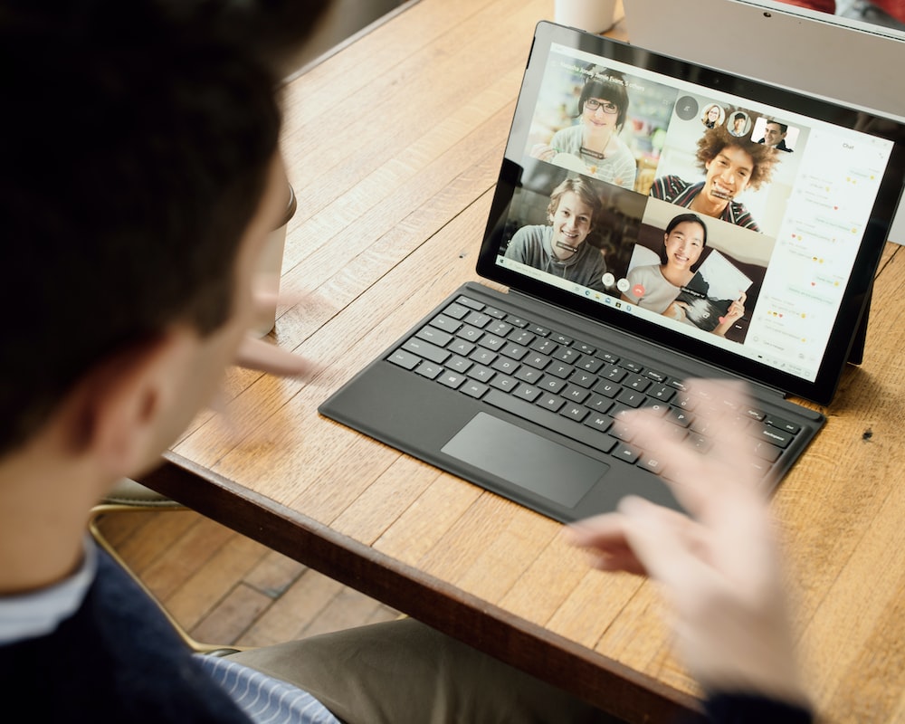 remote closing jobs, person in blue long sleeve shirt using black Surface, in a remote meeting